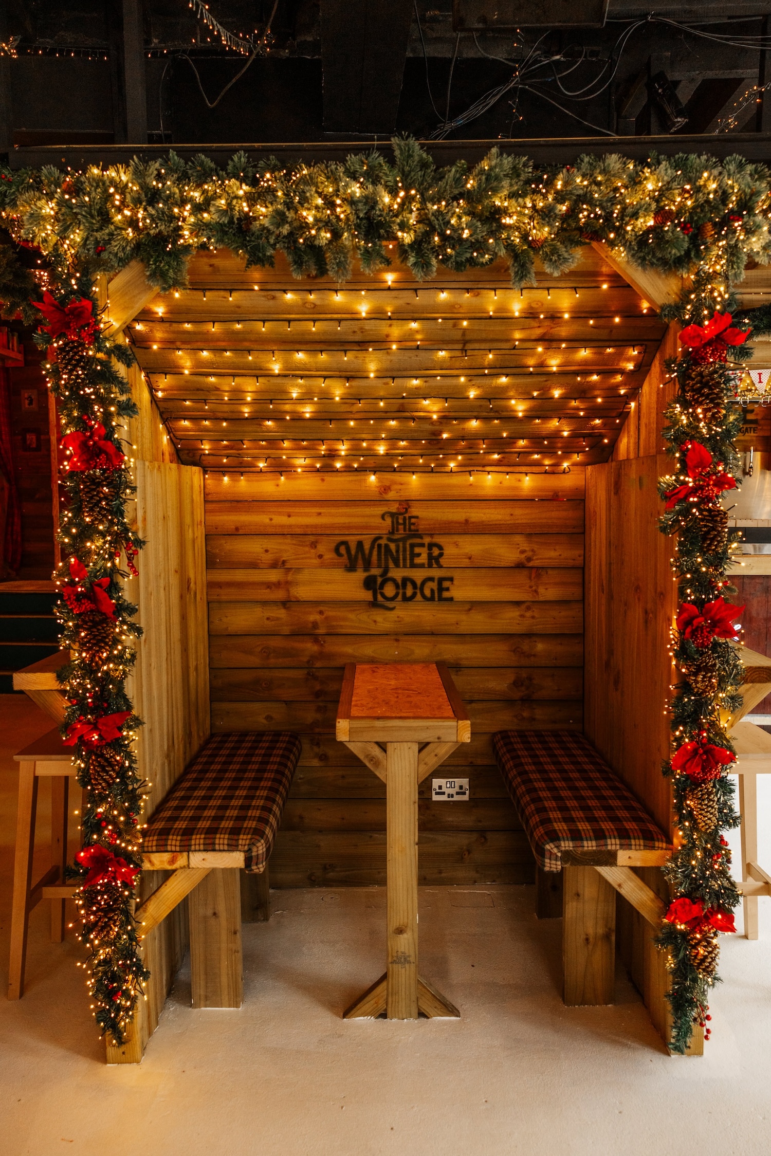 A cosy garlanded hut booth with tartan seats and fairy lights